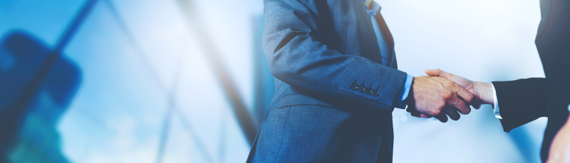Business people shaking hands in office, professional setting, suits, handshake